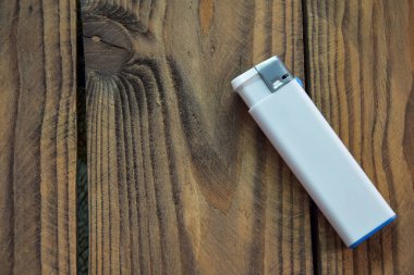 Tek kullanımlık beyaz bir çakmak ahşap bir arka planda duruyor. Beyaz bir çakmağın üst görüntüsü ve metni yerleştirecek bir yer. Boş çakmak maketi..