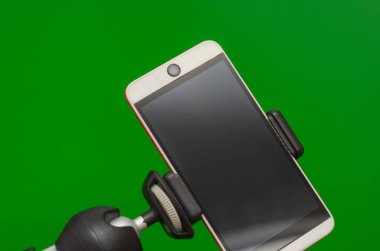 Bir tripoda akıllı telefon, telefondan fotoğraf ve video yayını. Yeşil arkaplan.