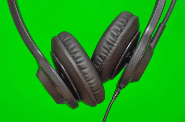 绿色背景下操作员远程工作用的黑色耳机 — 图库照片