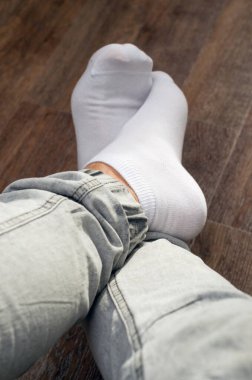 Ahşap zeminde kısa beyaz spor çoraplar ve pantolonlar içinde erkek bacakları.