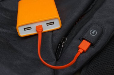 USB turuncu kablo ve sırt çantasında güç bankasıyla yükleniyor. Seyahat ederken aletlerinizi şarj edin..