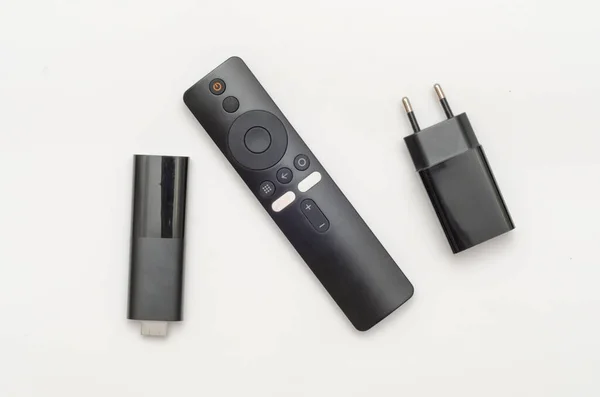 Siyah hdmi TV kutusu, şarj aleti ve beyaz arkaplanda uzaktan kumanda