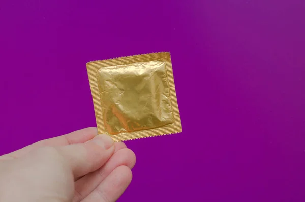 Uusi Kondomi Mies Kädessä Violetti Tausta — kuvapankkivalokuva