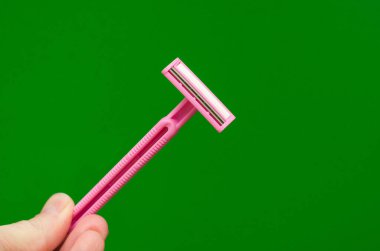 Yeşil arka planda tek kullanımlık pembe tıraş bıçağı.