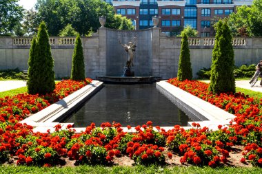 Saratoga Springs, NY - USA - Aug 3, 2022  A wide view of the  graceful bronze statue of a winged woman, The Spirit of Life. Standing on a niche of white marble with a balustraded terrace above.