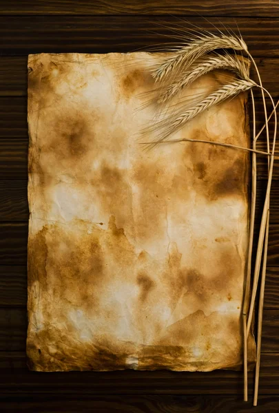 Tarwe op de oude houten tafel en oud papier — Stockfoto