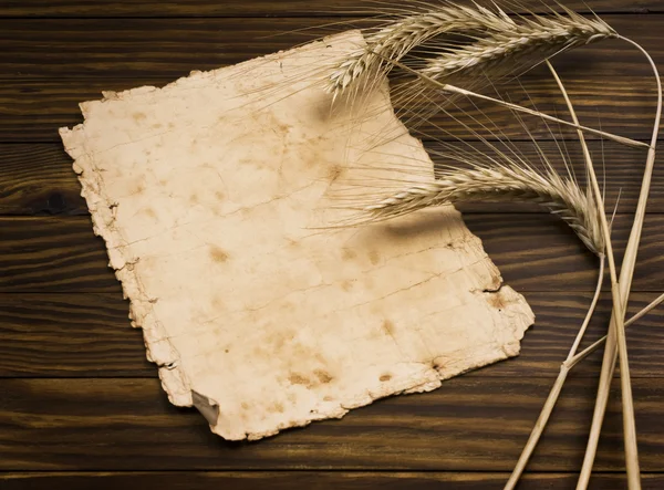 Wheat on the old wooden table and old paper — Stock Photo, Image
