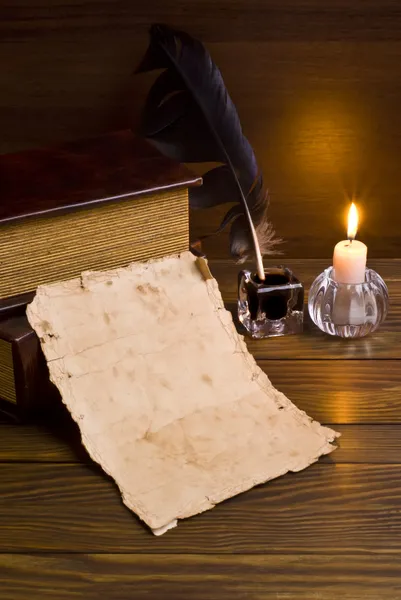 Pluma, papel viejo y vela sobre fondo de madera — Foto de Stock