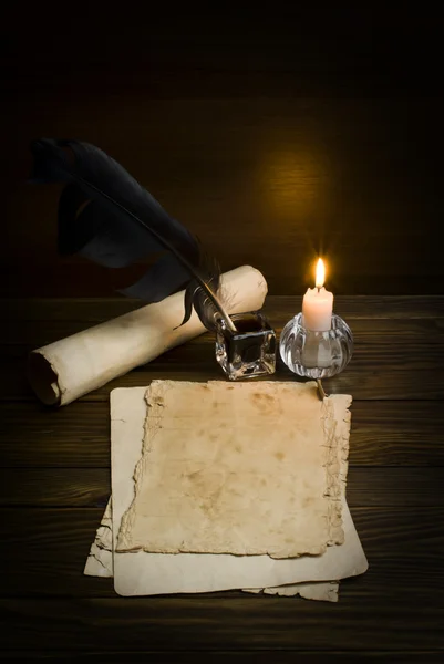 Feather, old paper and candle on a wooden background Royalty Free Stock Images