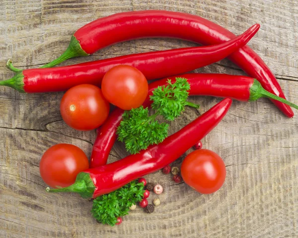 Tomat och red hot chili peppers i gamla murbruk på gamla träbord — Stockfoto
