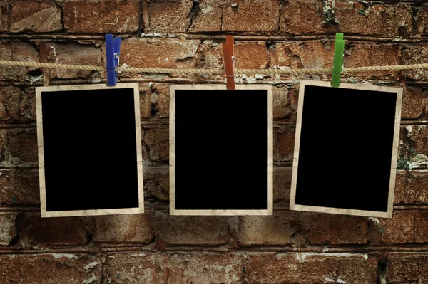 Εικόνες σε ένα σχοινί με μανταλάκια, με διαδρομή αποκοπής για εικόνες, μπροστά από έναν τοίχο από τούβλα — Φωτογραφία Αρχείου