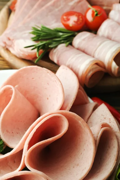 Tranches de jambon frais avec laitue et tomate cerise sur la planche de bois — Photo