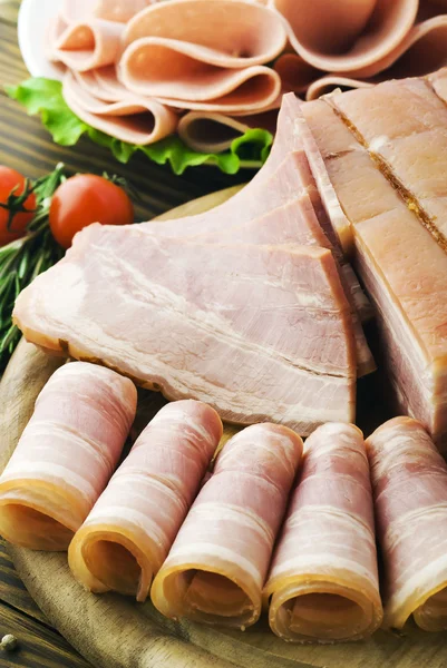 Verse ham segmenten met lattuce en cherry tomaat op de houten bord — Stockfoto