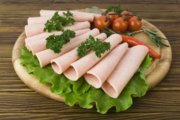 Fatias de presunto fresco com lattuce e tomate cereja na tábua de madeira — Fotografia de Stock