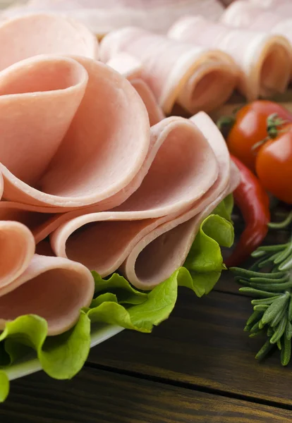 Fette di prosciutto fresco con lattuce e pomodoro ciliegia sul tagliere di legno — Foto Stock