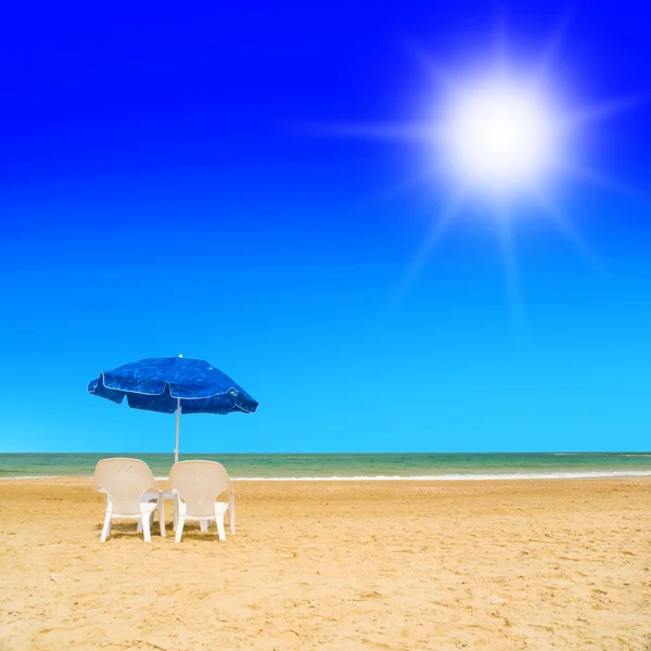 Pair of sun loungers and a beach umbrella on a deserted beach — Stock Photo, Image