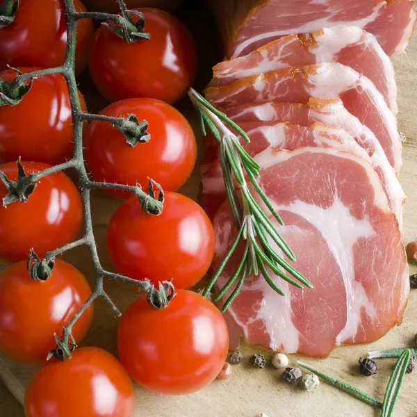 Delizioso prosciutto affumicato su tavolo in legno con rosmarino — Foto Stock