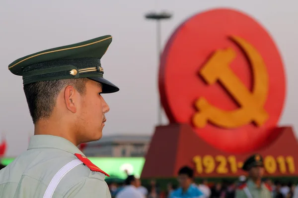 En soldat står vakt mot bakgrund av de kommunistiska symbolerna på Himmelska fridens torg i Peking, Kina Stockbild