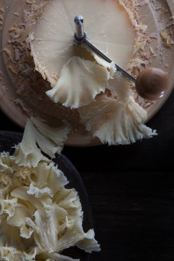 İsviçre peyniri tete de moine dilimlenmiş talaş. Lezzetli peynir talaşlarını dilimlemek ve tatmak için bir kazıyıcı ya da kız bıçağı. Dikey fotoğraf. Özel peynir. Üst görünüm..