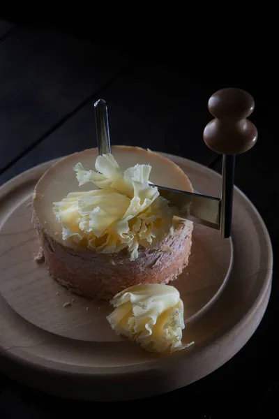 Tahta bir tahtanın üzerinde peynir tete de moine. Peynir dokusuna yakın çekim. Üst Manzara. Siyah arkaplanda dikey fotoğraf. Boşluğu kopyala.