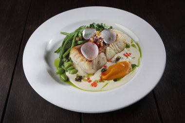 Beyaz soslu ve fasulyeli turna balığı. Beyaz bir tabak. Restoran için menü. Bir tabak kirpik balığı. Sağlıklı ve düşük kalorili yiyecekler. Uzayı kopyalayın. Düz yatıyordu.