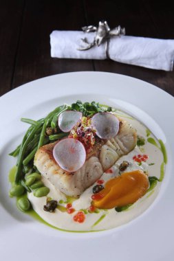 Beyaz soslu ve fasulyeli levrek. Restoran için beyaz tabak. Sağlıklı ve düşük kalorili yemek. Fasulyeli balık tabağı..