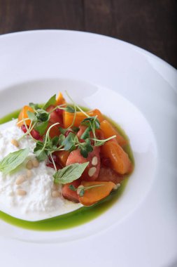 Hurma ve domatesli Straciatella. Beyaz tabakta yemek. Restoran menüsü konsepti. Yakın plan..