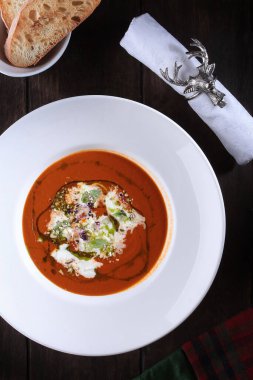 Stracatella peynirli kremalı domates çorbası. Beyaz tabakta yemek. Kızarmış ekmek parçaları. Restoran menüsü konsepti. Dikey fotoğraf. Beyaz peçeteli şenlik masası..