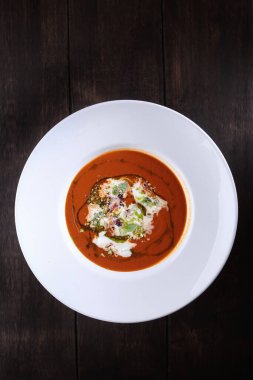 Stracatella peynirli kremalı domates çorbası. Beyaz tabakta yemek. Kızarmış ekmek parçaları. Restoran menüsü konsepti. Dikey fotograf. Kopyalama alanı olan üst görünüm. Düz zemin. Dikey fotoğraf. Ahşap zemin..