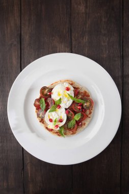 Tortilla üzerine burrata peyniri, vişneli domates ve fesleğen. Lezzetli aperatif. Kopyalama alanı olan üst görünüm. Düz zemin. Dikey fotoğraf. Ahşap zemin..