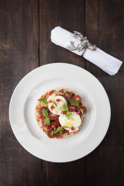 Tortilla üzerine burrata peyniri, vişneli domates ve fesleğen. Lezzetli aperatif. Geyik kafası şeklinde metal halkalı beyaz pamuk peçete. Kutlama masası ayarları. Üst manzara. Düz taban. Dikey