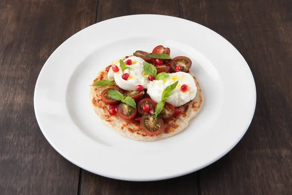 Tortilla üzerine burrata peyniri, vişneli domates ve fesleğen. Lezzetli iştah açıcı. Ahşap arka plan..