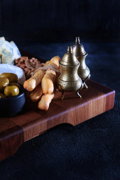 Grissini with olives on wooden board. Selective focus. Dark background. Vertical photo. — Fotografia de Stock