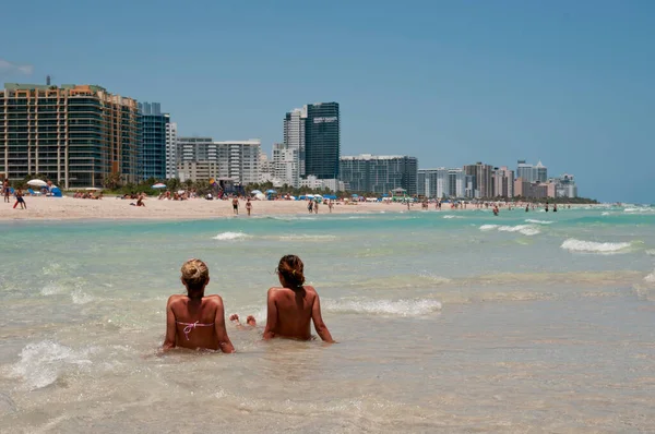Miami sahilinde sıcak bir günde iki genç kadın denizde dinleniyor.