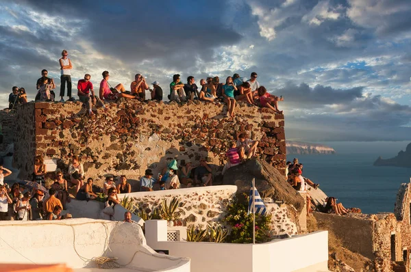 Oia, Santorini, Yunanistan 'da gün batımını izleyen gezginler. Yunanistan 'ın Oia kentinde gün batımını izleyen bir grup insan