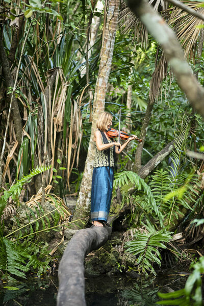 A Female Musician Balancing on a Log Plays Violin in the Tropical Forest in Mexico
