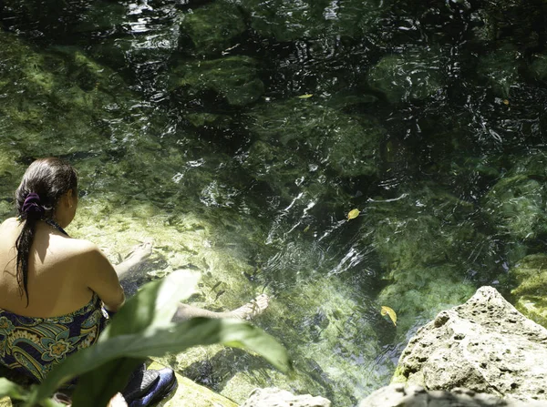Rear view shot of an indigenous woman cooling off in a cenote in the tropical forest in Mexico