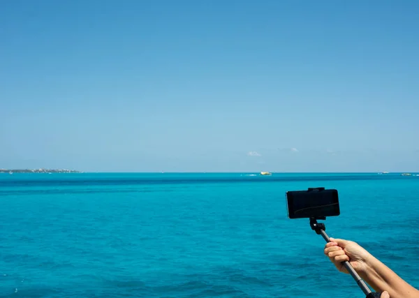 Akıllı telefonlu bir kadının kolu Meksika 'da Karayip Denizi' nde yelken açarken video çekiyor.