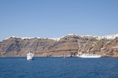 Santorini 'nin sahil kayalıklarının genel görünümü, sudaki bir tekneden görüldüğü gibi..