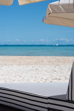 Meksika 'daki Mujeres Adası' ndaki tropikal bir plajda şık bir güneş yatağı ve şemsiye.