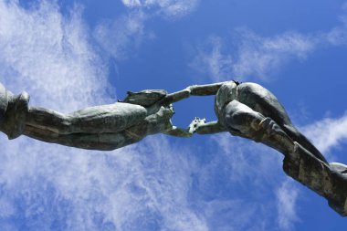 Bronze statue against the blue sky of the two lovers in Playa del Carmen, Mexico. Shot from below. Hand holding statues