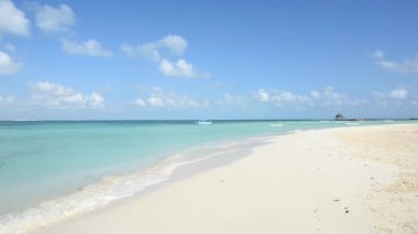 Güneşin doğuşunda ıssız tropikal plajda mavi gökyüzüne demirlemiş bir tekne, Isla Mujeres, Meksika. Yatay HD video