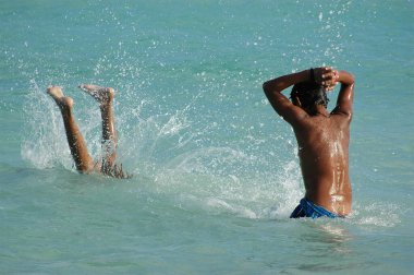 Denizde iki üstsüz Meksikalı çocuğun akrobatik atlayışları. Seçici odak