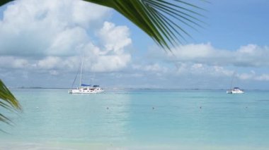 moored boat in the turquoise calm sea near the tropical small island with white beaches and palms. FullHD footage real-time