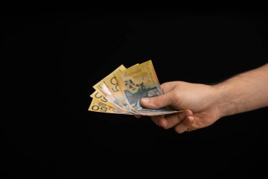 Sağ taraftan siyah bir arka planda Avustralya doları veren bir adamın eli.
