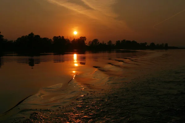 川に沈む夕日が美しく水面に浮かぶ船の痕跡が — ストック写真