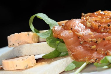 Kızarmış ekmek, füme kırmızı balık ve beyaz tabak stüdyosunda yeşillikler.