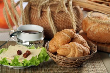 Hamur işleri, meyveler, peynirler, fındıklar, buğdaylar ve marullar masada.