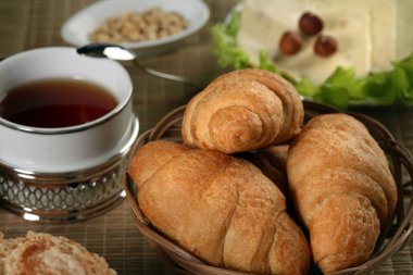 Hamur işleri, meyveler, peynirler, fındıklar, buğdaylar ve marullar masada.
