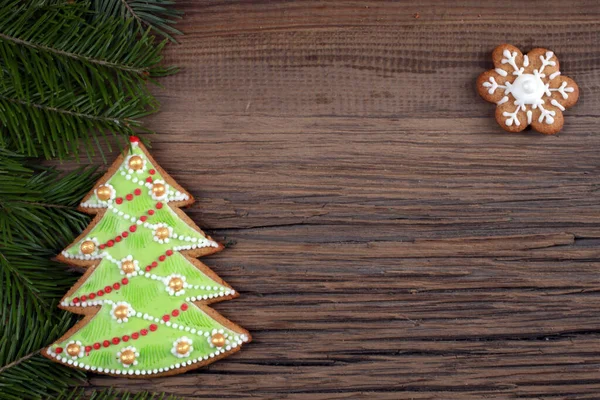 在神奇的圣诞假期里 冷杉枝干和带花纹的姜饼的特写静止不动 背景是一个木制的木板工作室 — 图库照片